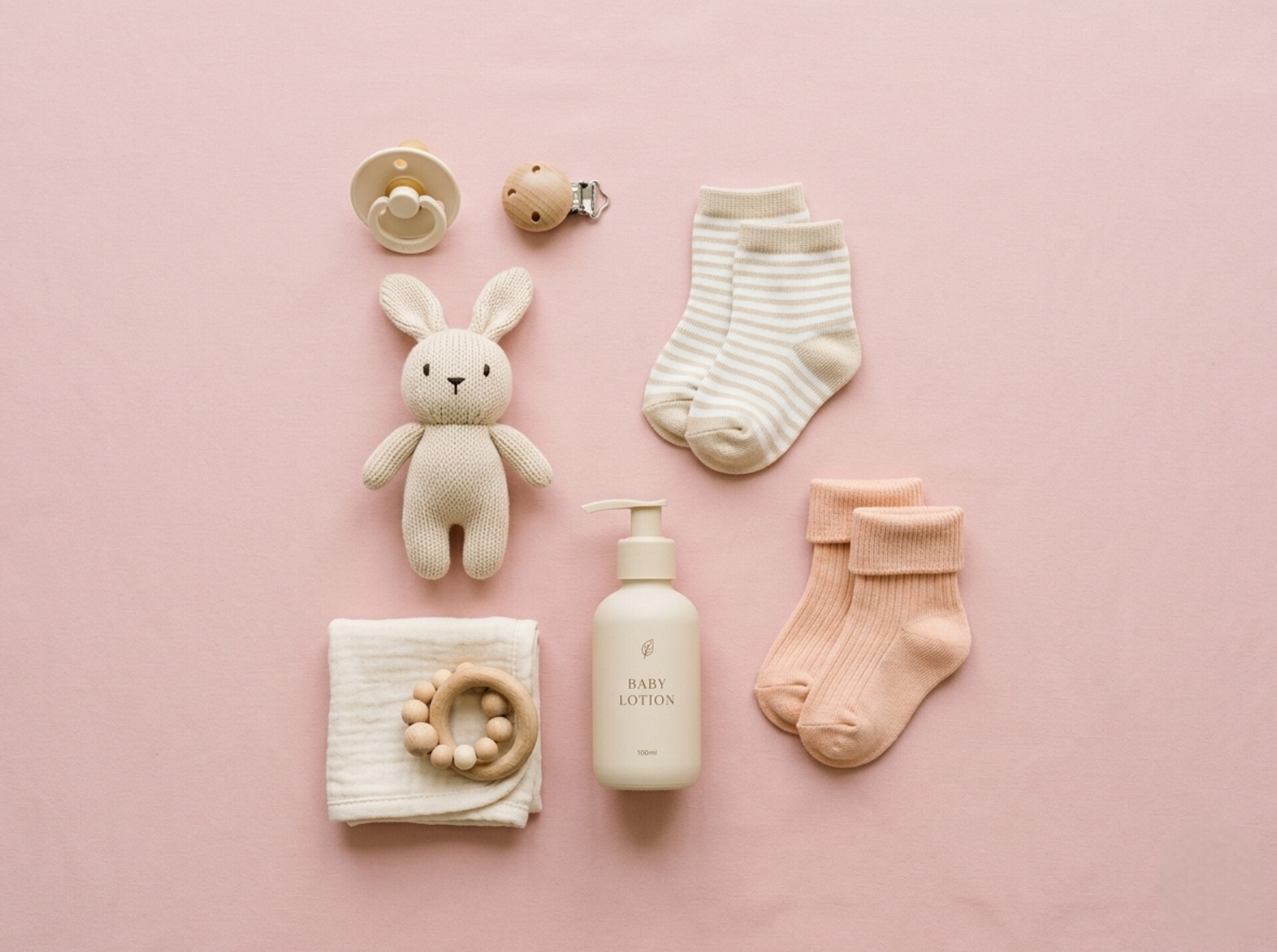 Baby essentials flat lay - pacifier, knit bunny, lotion, socks